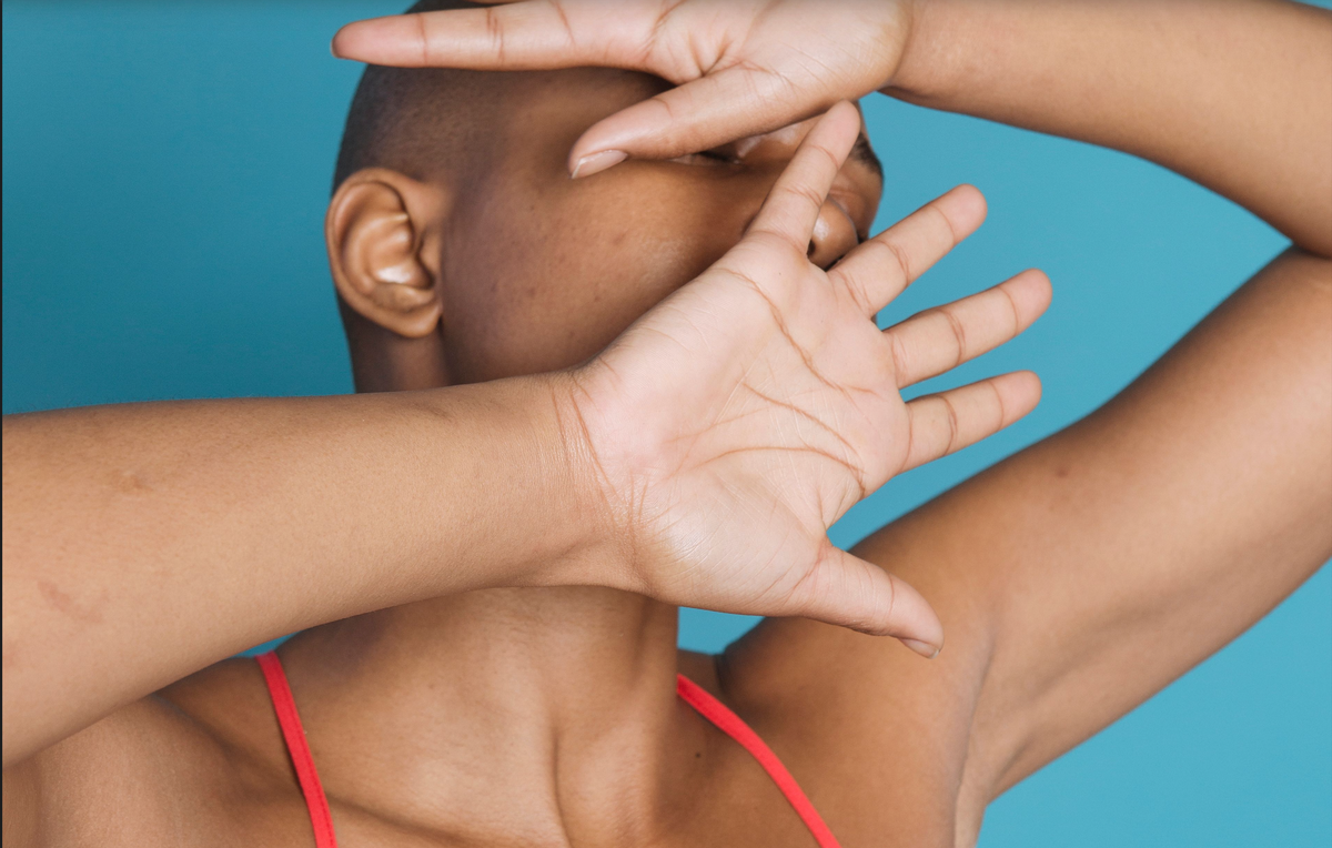 Women seemingly holding off by cover her face with her handpalms outward.