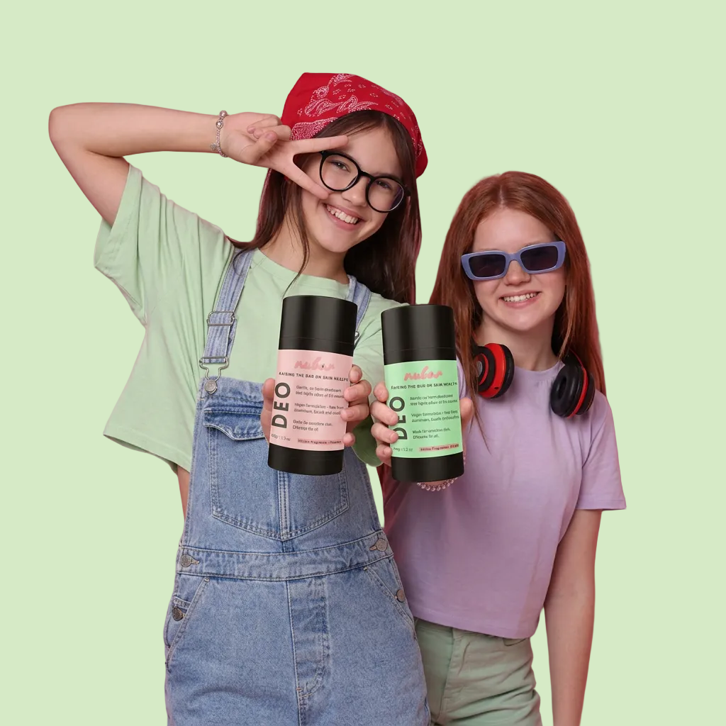 Two young girls posing against a solid pink background, holding black cylindrical DEO deodorant cans. The girl on the left wears a light green t-shirt, denim overalls, a red bandana, and glasses, while the girl on the right wears a lavender t-shirt, blue-tinted sunglasses, and red headphones around her neck.